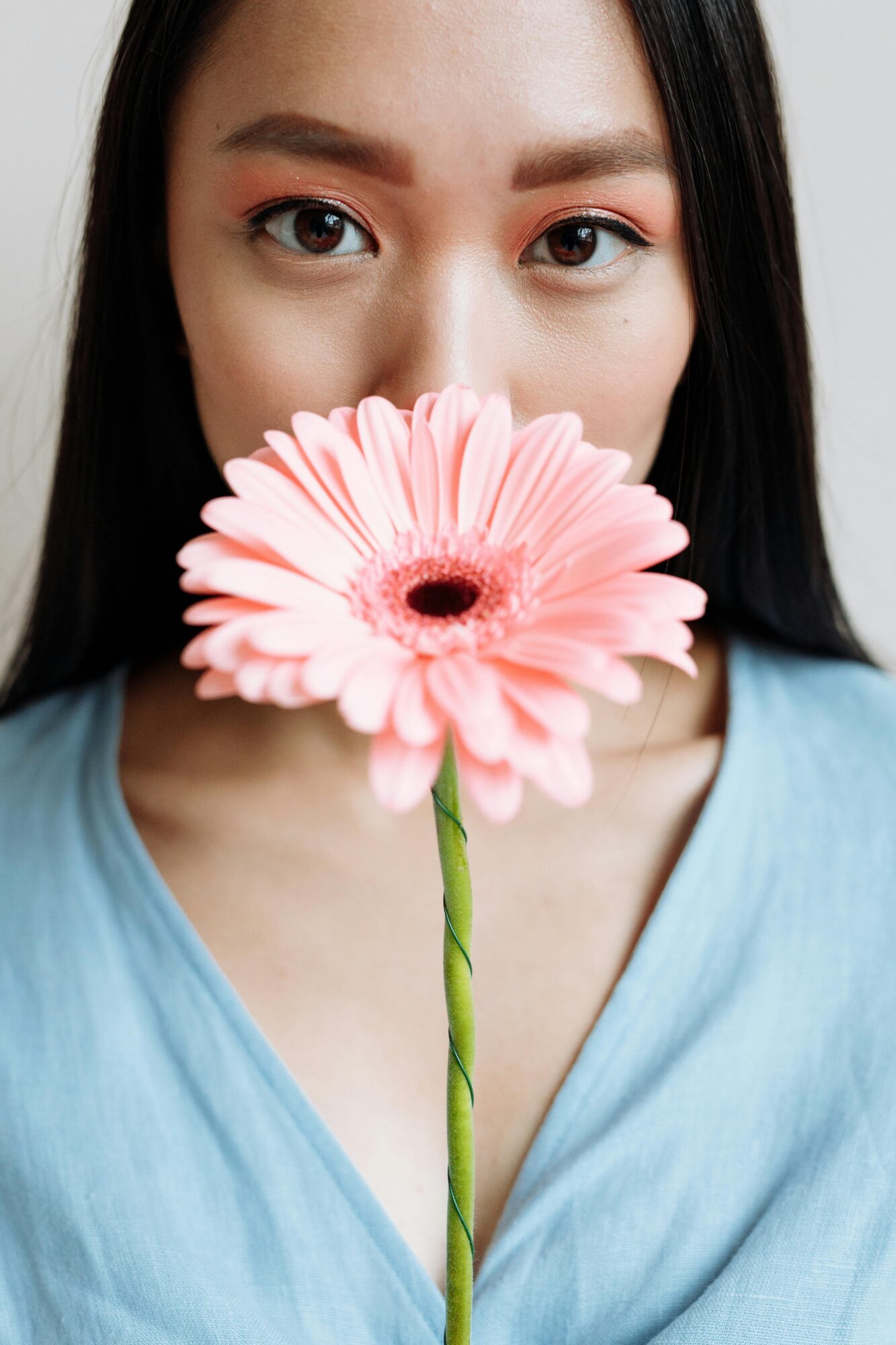 woman with pink flower in front of her face